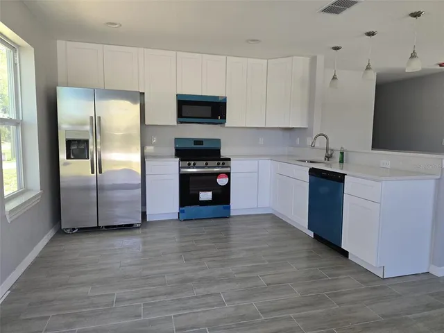 a kitchen with stainless steel appliances granite countertop a refrigerator a stove top oven a sink and dishwasher with wooden floor