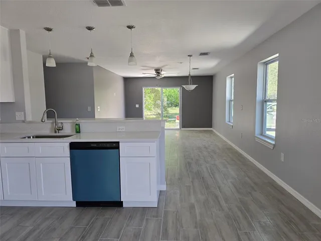a kitchen with kitchen island granite countertop a sink cabinets and wooden floor