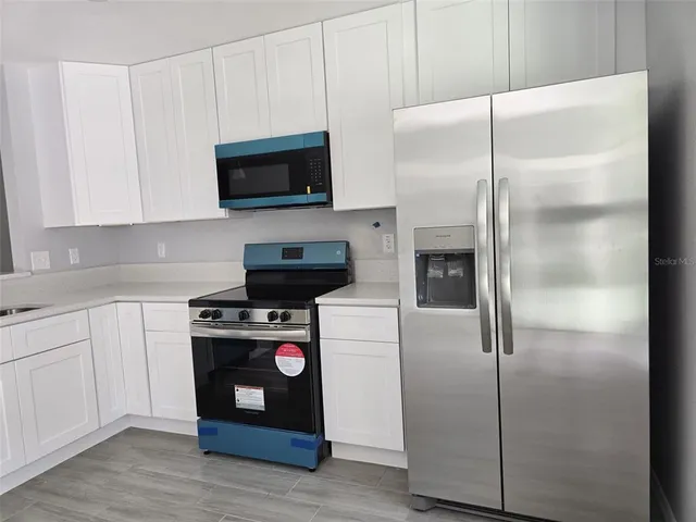 a kitchen with a refrigerator stove and white cabinets