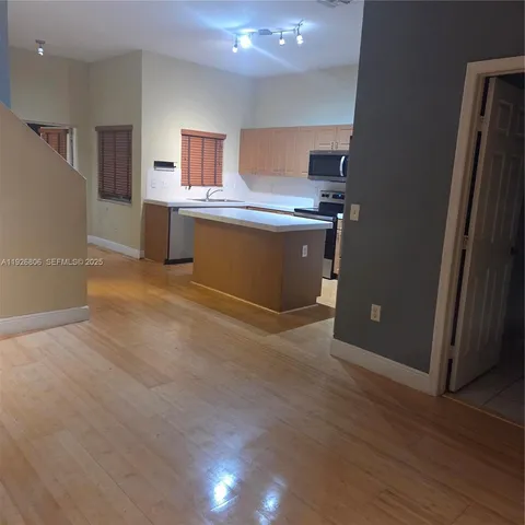 a view of kitchen with stainless steel appliances cabinets and wooden floor