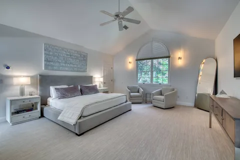 a spacious bedroom with a bed mirror and window