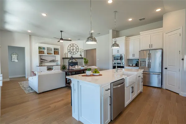 a large kitchen with stainless steel appliances kitchen island a stove a refrigerator a oven and a dining table with wooden floor