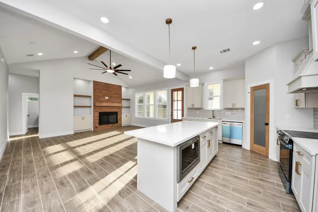 a large kitchen with granite countertop lots of counter space wooden floor and stainless steel appliances