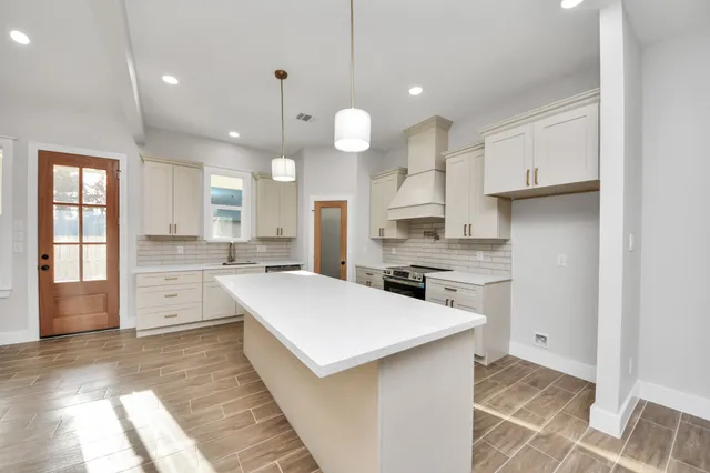 a large kitchen with kitchen island a stove a sink a refrigerator and a fireplace