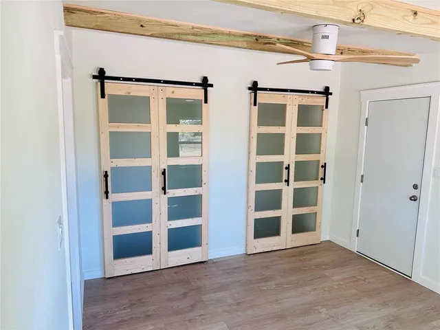 a view of an empty room with wooden floor and closet