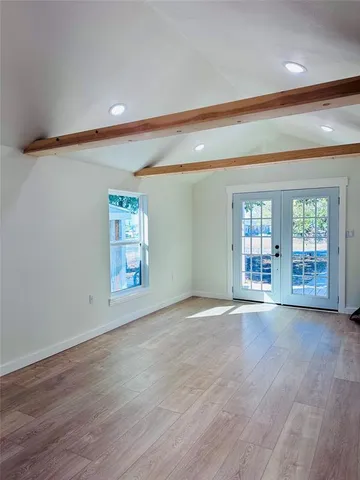a view of an empty room with window and wooden floor