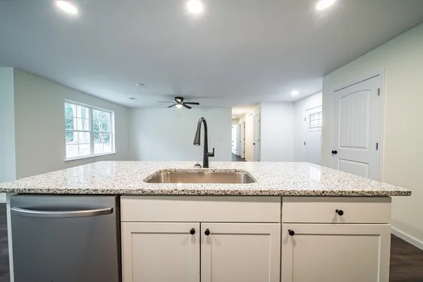 a bathroom with a granite countertop sink and white cabinets