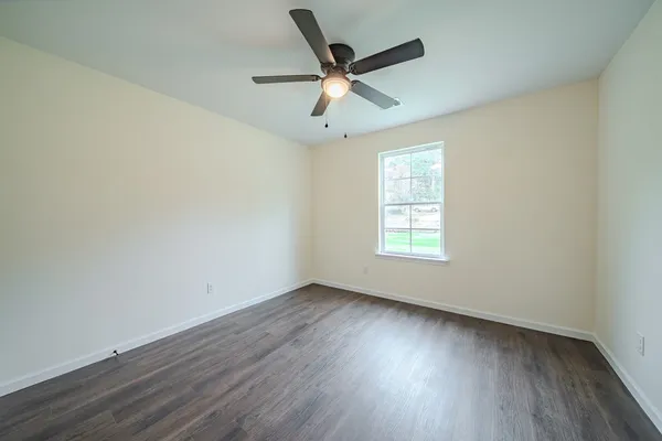 an empty room with wooden floor and a ceiling fan