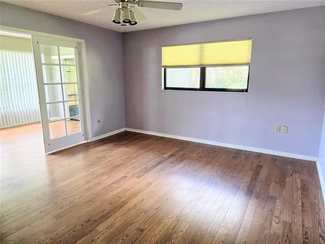 a view of an empty room with wooden floor and a window