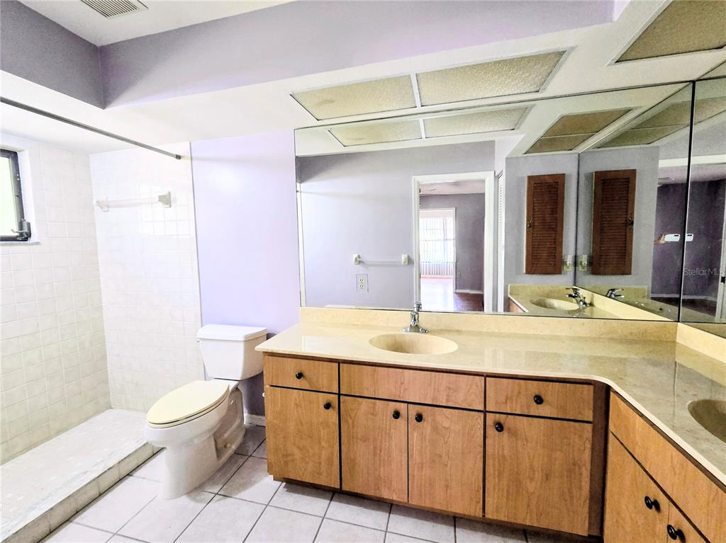 3239 Lori Lane, Unit 3239 New Port Richey, FL 34655 - Photo 16 of 33 a bathroom with a granite countertop sink a toilet a mirror and shower