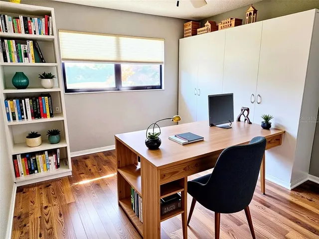 a view of an empty room with wooden floor and a bathroom