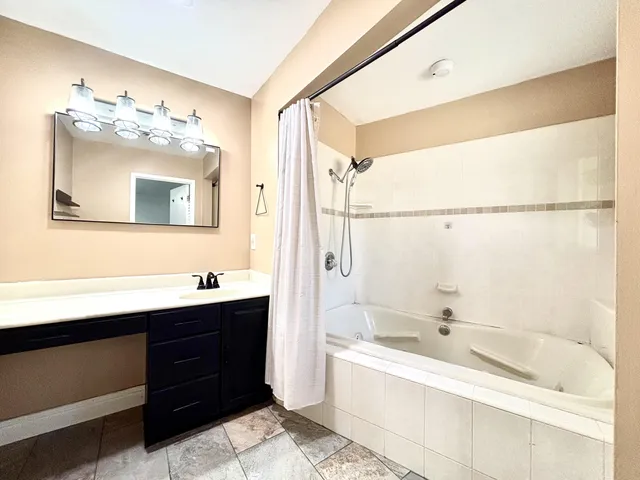 a bathroom with a tub a sink and mirror