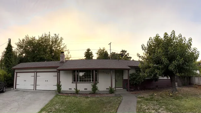 a view of a house with a yard and large tree