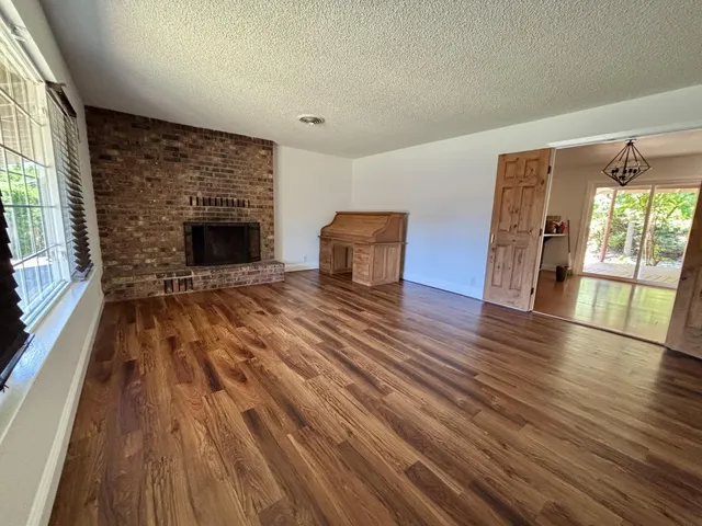 a view of empty room with wooden floor and fireplace