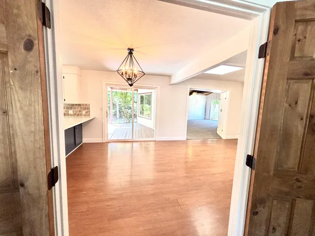 a view of a hallway with wooden floor and a bathroom