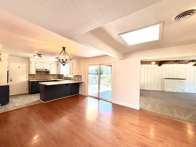 a living room with stainless steel appliances kitchen island granite countertop a sink cabinets and wooden floor