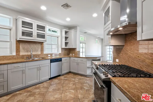 a kitchen with stainless steel appliances granite countertop a stove a sink and a microwave
