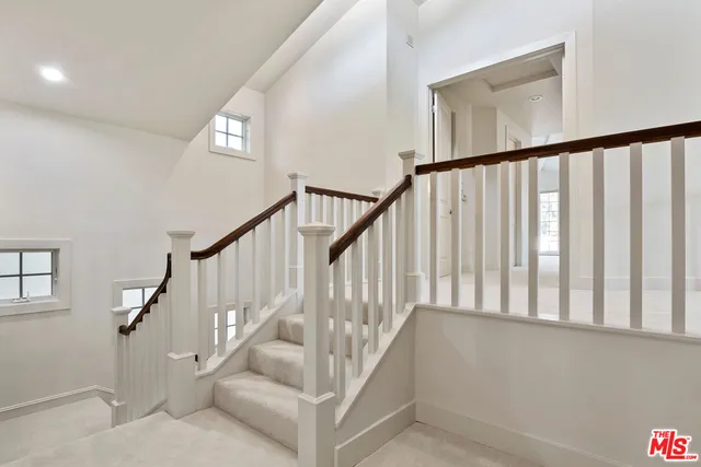 a view of staircase with railing and white walls