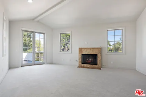 an empty room with windows and fireplace