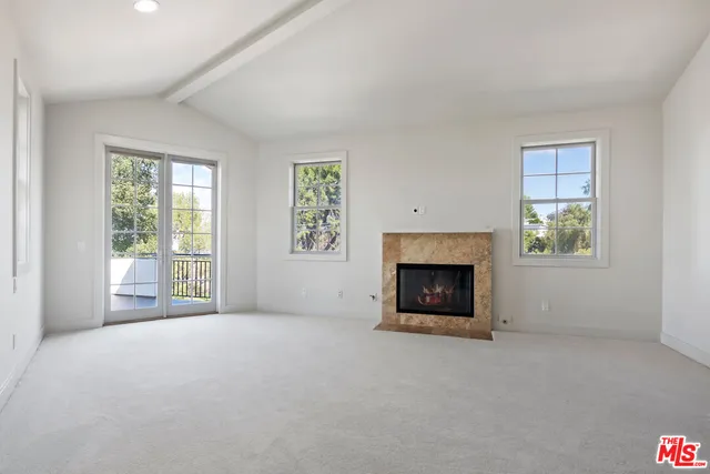 an empty room with windows and fireplace