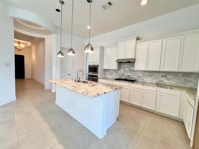 a large kitchen with kitchen island a stove a sink a center island and cabinets