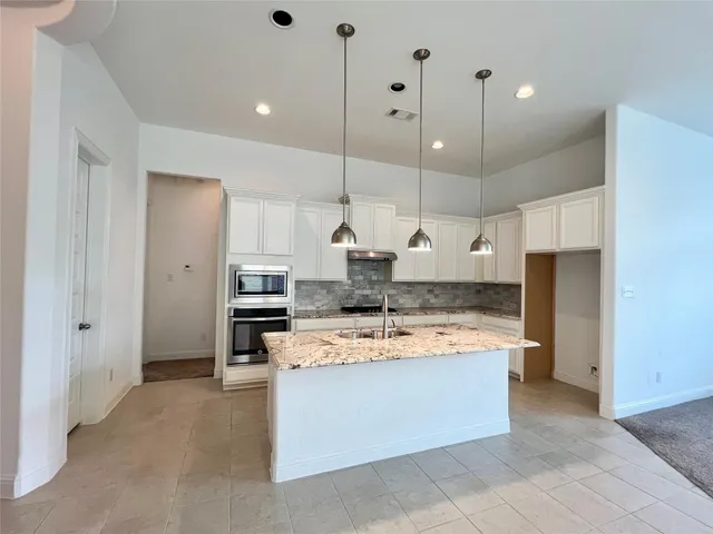 a large kitchen with kitchen island a stove a sink a refrigerator and a oven