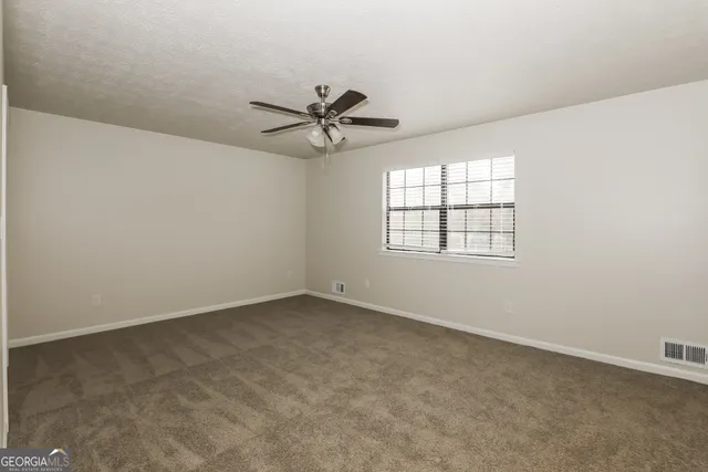 an empty room with windows and ceiling fan view