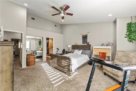 a spacious bedroom with a bed a couch and a potted plant