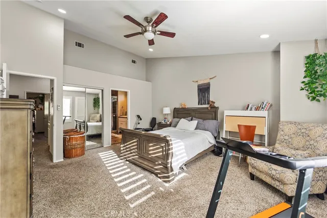 a spacious bedroom with a bed a couch and a potted plant