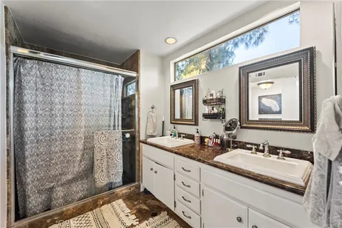 a bathroom with a granite countertop sink mirror and a shower