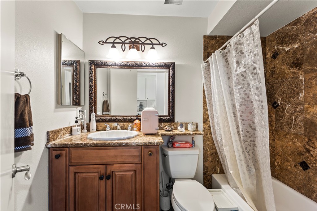 22617 Copper Hill Drive, Unit 121 Saugus, CA 91350 - Photo 19 of 24 a bathroom with a sink a toilet a mirror a vanity and shower