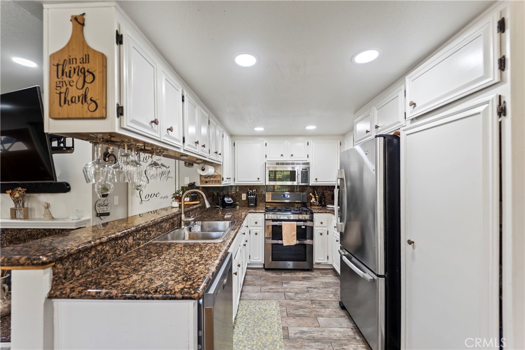 22617 Copper Hill Drive, Unit 121 Saugus, CA 91350 - Photo 6 of 24 a kitchen with stainless steel appliances granite countertop a refrigerator a stove and a sink with wooden floor