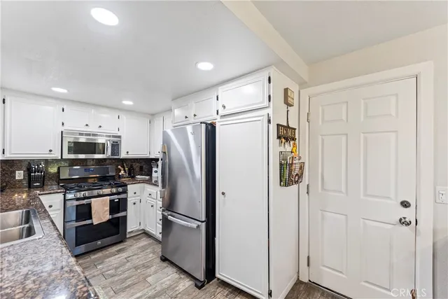 a kitchen with stainless steel appliances a refrigerator a stove top oven a sink and cabinets