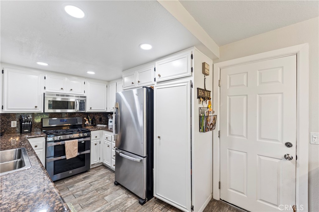 22617 Copper Hill Drive, Unit 121 Saugus, CA 91350 - Photo 9 of 24 a kitchen with stainless steel appliances a refrigerator a stove top oven a sink and cabinets