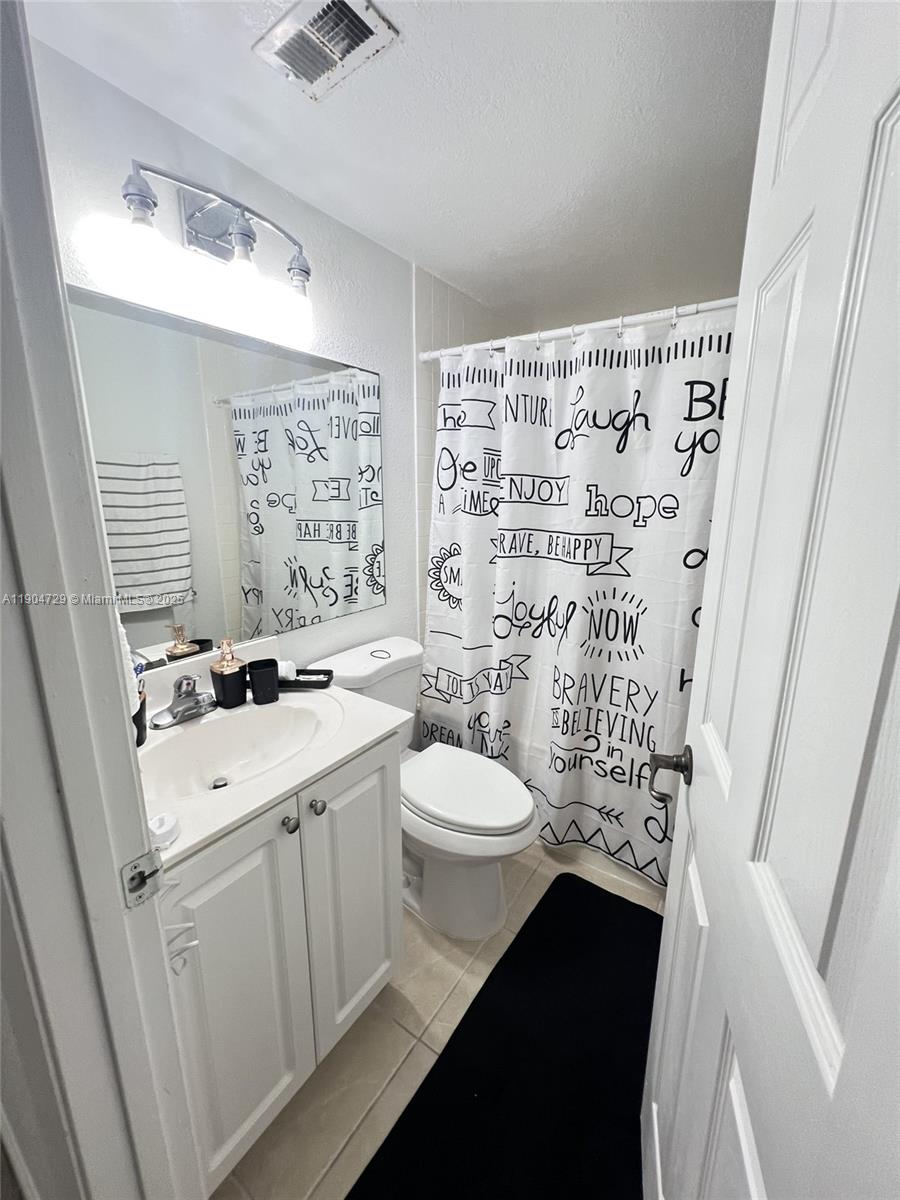 8116 Severn Drive, Unit C Boca Raton, FL 33433 - Photo 13 of 19 a bathroom with a sink a toilet a shower curtain and a shower curtain