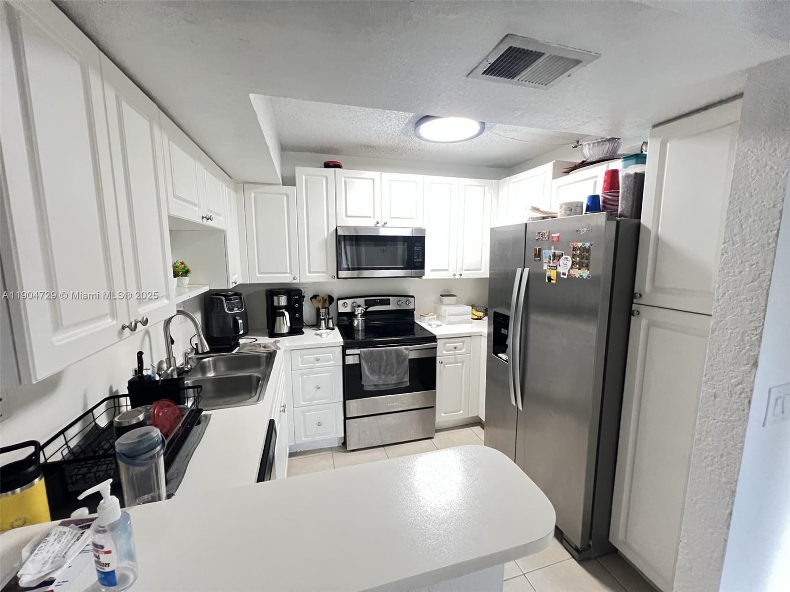 8116 Severn Drive, Unit C Boca Raton, FL 33433 - Photo 5 of 19 a kitchen with stainless steel appliances a refrigerator a stove a microwave and cabinets