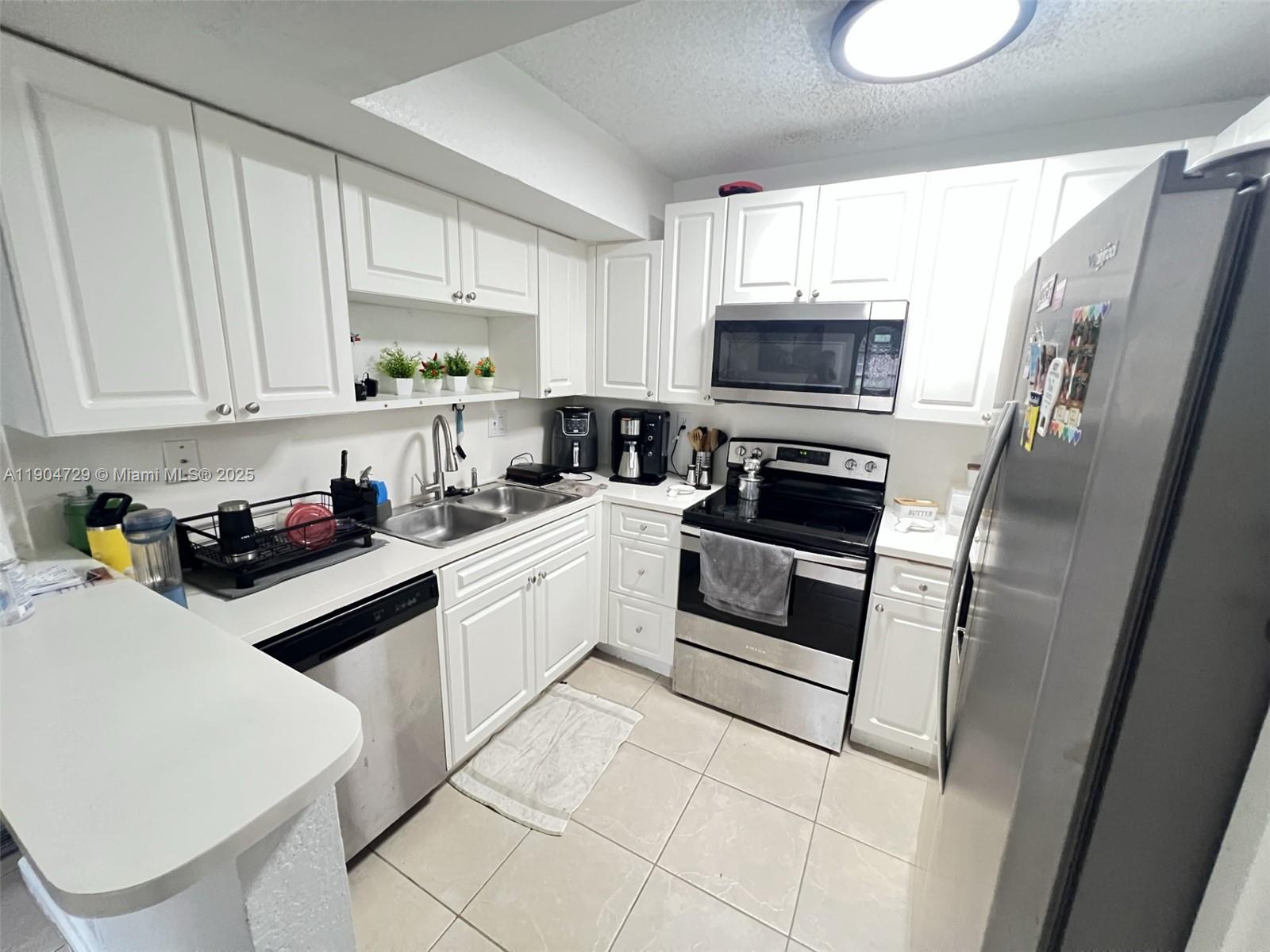 8116 Severn Drive, Unit C Boca Raton, FL 33433 - Photo 6 of 19 a kitchen with white cabinets and white appliances