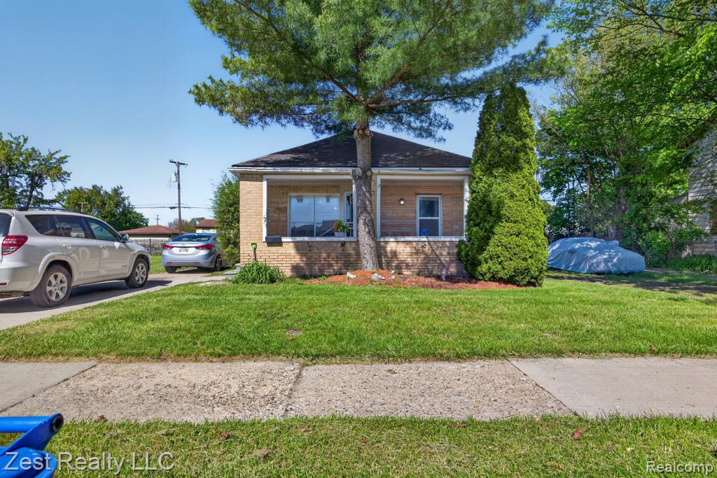 Bungalow-style home with covered porch, a front yard, and brick siding