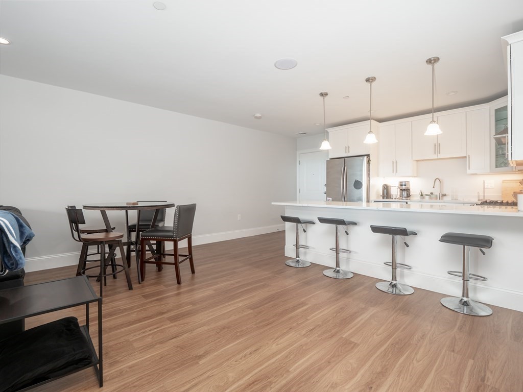 45 L Street, Unit 21 Boston, MA 02127 - Photo 7 of 23 a kitchen with kitchen island stainless steel appliances a dining table chairs sink and cabinets