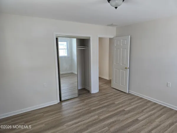 a view of an empty room with wooden floor and closet