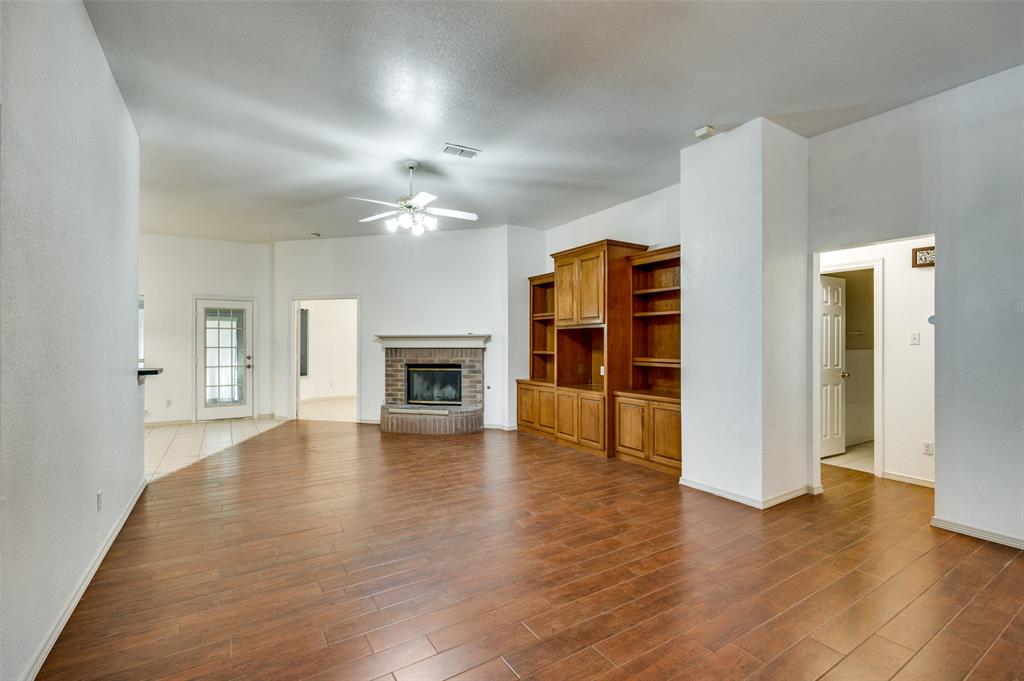6812 Cold Water Canyon Road Fort Worth, TX 76132 - Photo 3 of 12 an empty room with wooden floor and fireplace