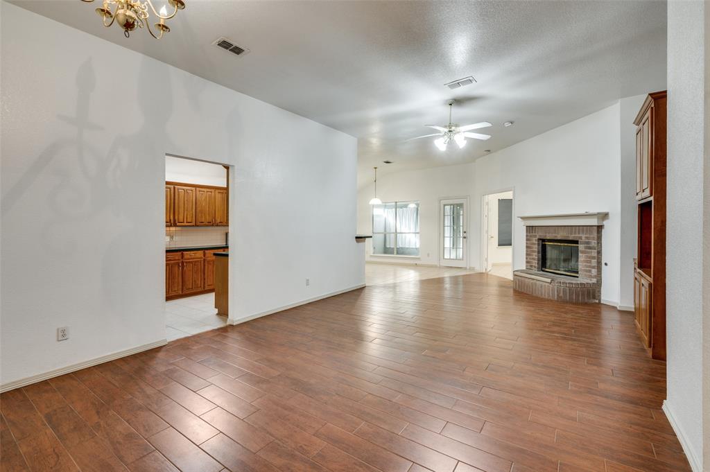 6812 Cold Water Canyon Road Fort Worth, TX 76132 - Photo 4 of 12 an empty room with wooden floor fireplace and windows