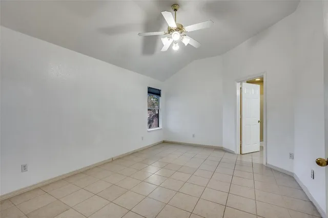 an empty room with a chandelier fan and windows