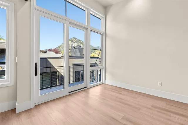 an empty room with wooden floor and windows