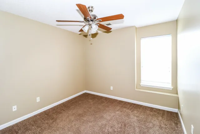 an empty room with a window and a fan