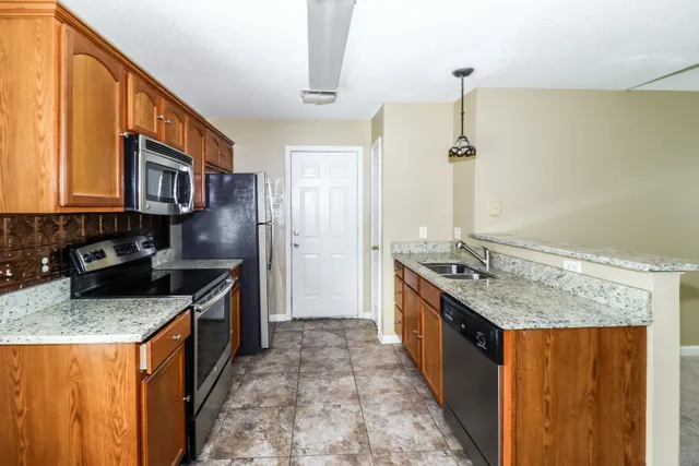 a kitchen with stainless steel appliances granite countertop a sink stove and refrigerator