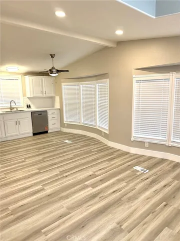 an empty room with kitchen view and wooden floor