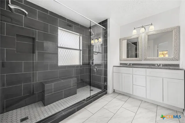 a bathroom with a granite countertop sink a mirror and a shower