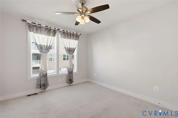an empty room with chandelier fan and windows