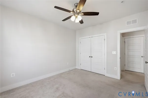 an empty room with chandelier fan and closet